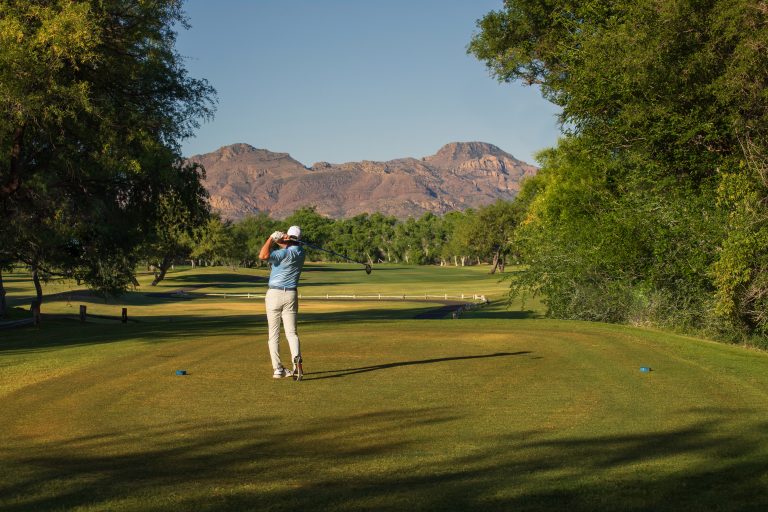 Golfer teeing off under the Santa Rita mountains at Tubac