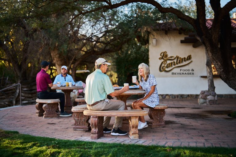 Guests having coffee on the La Cantina patio under mesquite trees